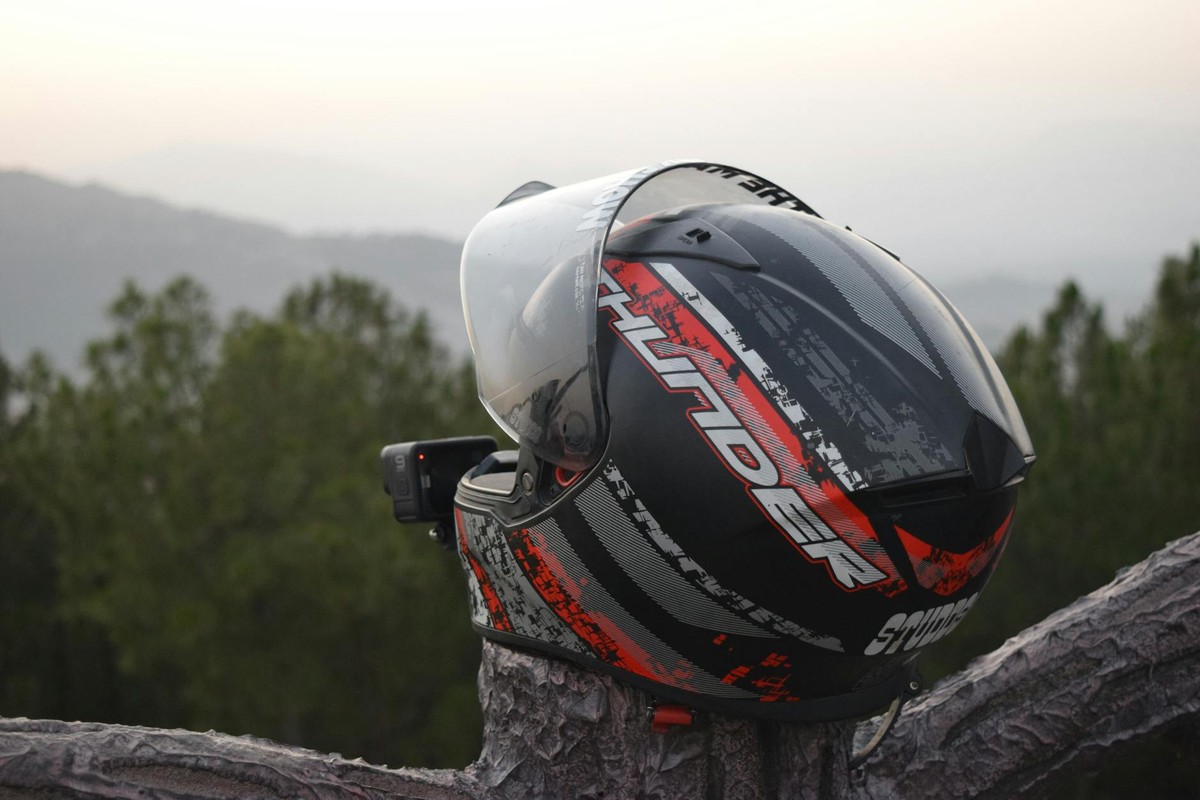 Close-up of a motorcycle helmet on a tree trunk with scenic outdoor backdrop.