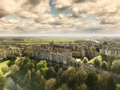 A breathtaking aerial shot of Arundel Castle surrounded by lush greenery and under a dramatic sky.