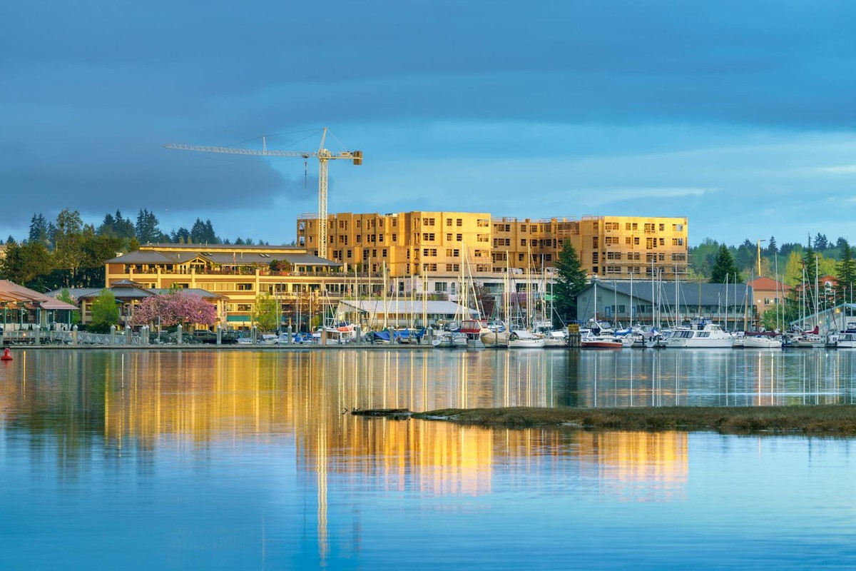 Scenic waterfront view of boats, buildings, and construction crane at sunset.