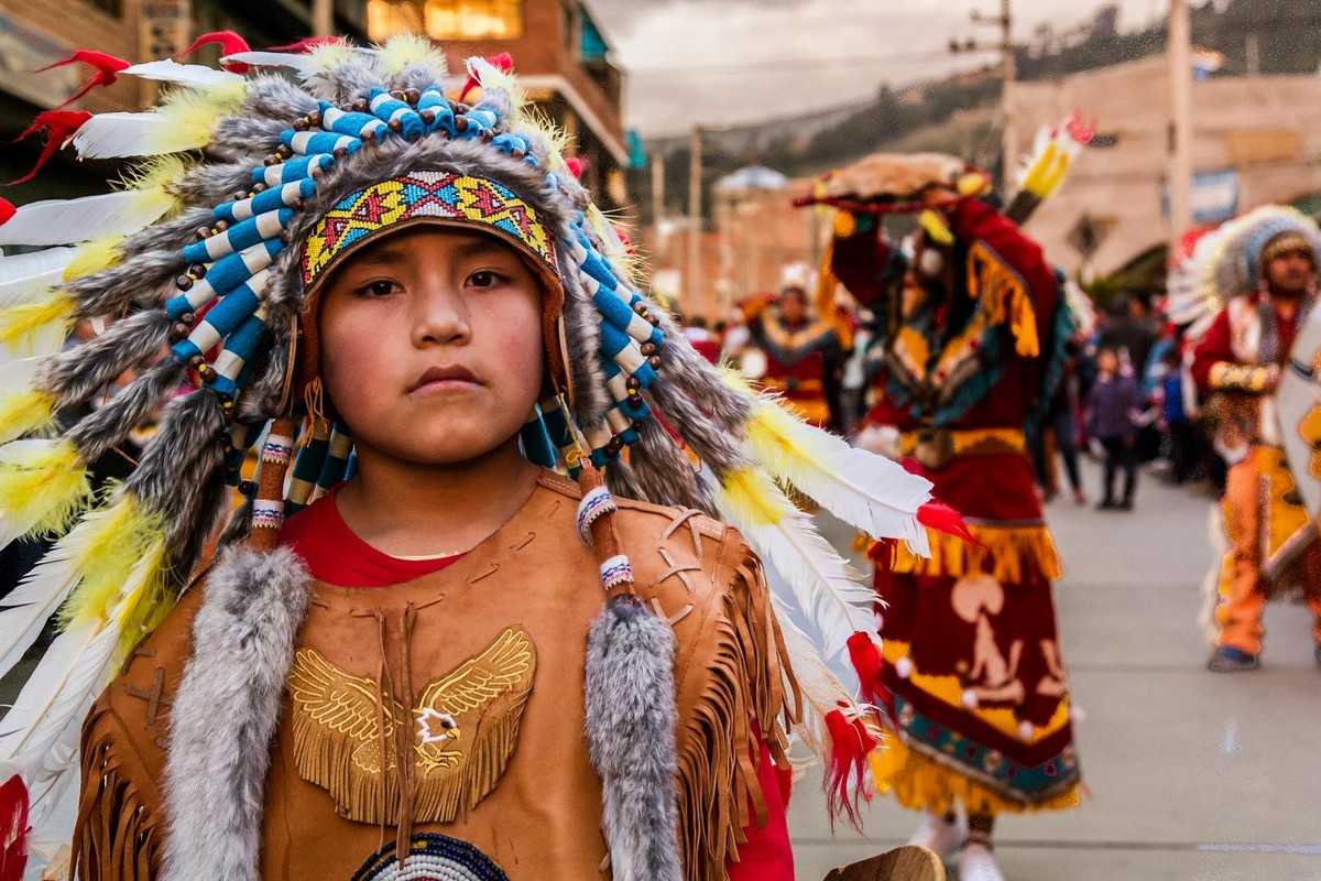 Young participant in traditional attire at a vibrant cultural parade, showcasing intricate costumes and headdresses.