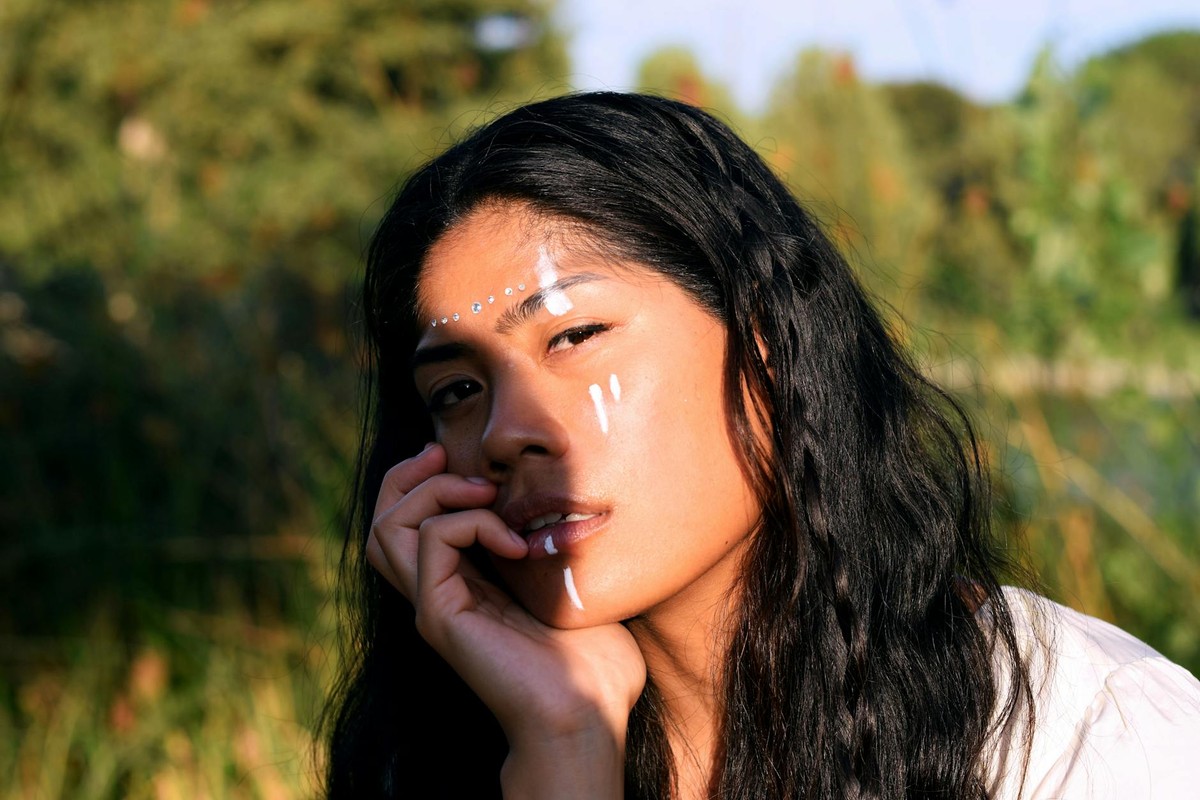 Close-up portrait with artistic face paint and natural setting.
