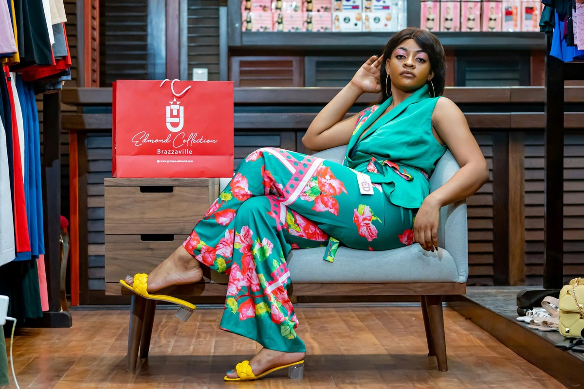 Stylish African woman posing in vibrant floral outfit in a Brazzaville boutique.