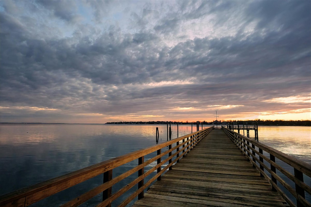 A breathtaking twilight scene at the Norwalk pier in Connecticut, capturing the tranquil waters and dramatic sky.