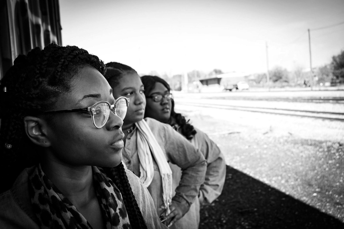 Three women outdoors in a black and white photo, showcasing strong presence and unity.