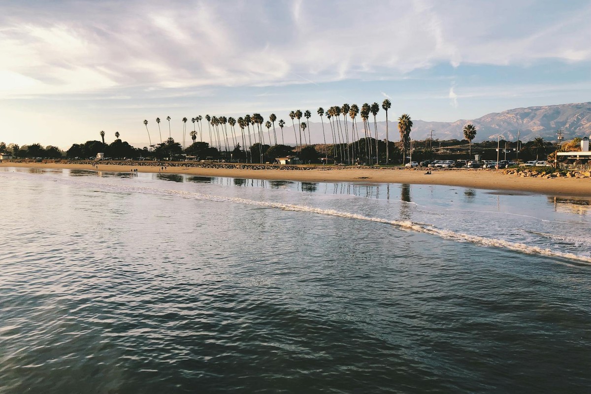 Stunning beach with palm trees and mountains at sunset. Perfect for nature lovers.