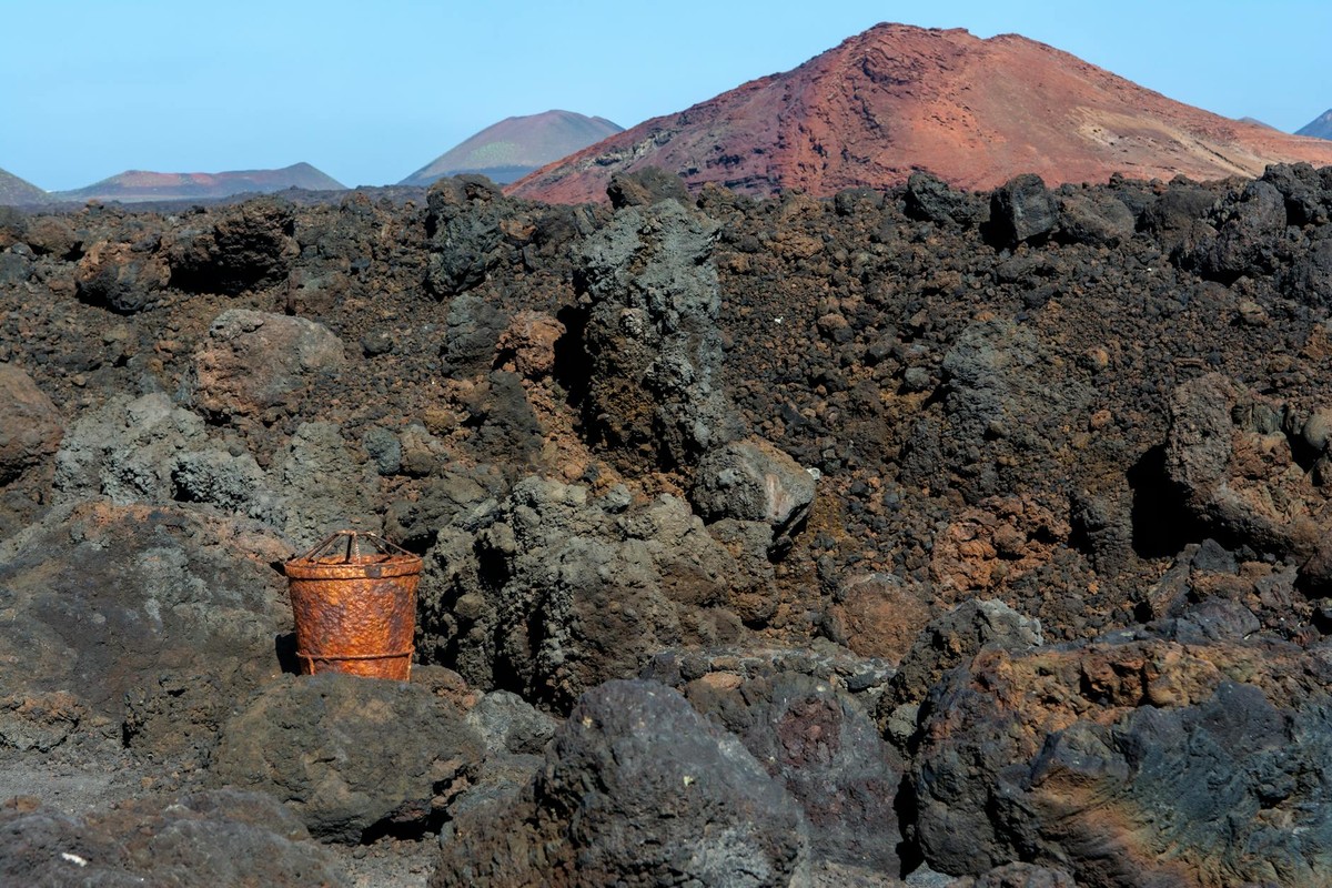 Rugged volcanic terrain of Lanzarote with a rusty container adding contrast to the arid, desolate landscape.