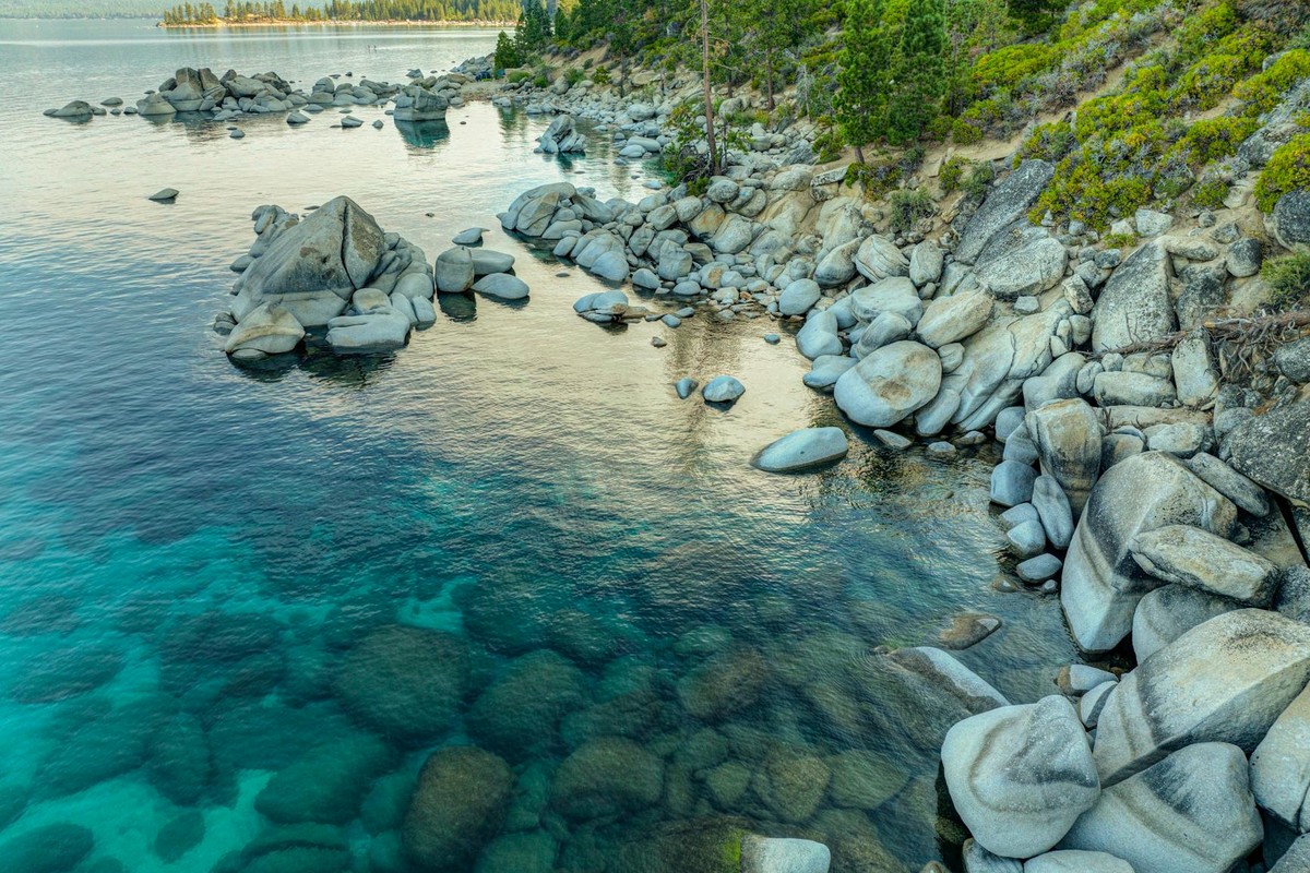 Peaceful view of Lake Tahoe's clear waters and rocky shoreline in summer.