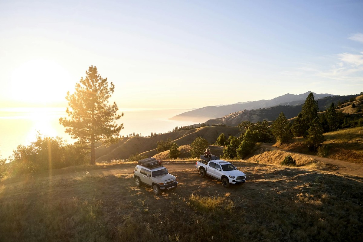 Two vehicles parked on a California mountain with a stunning sunset view.