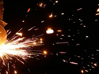 Close-up of vibrant sparks from an angle grinder against a dark background.