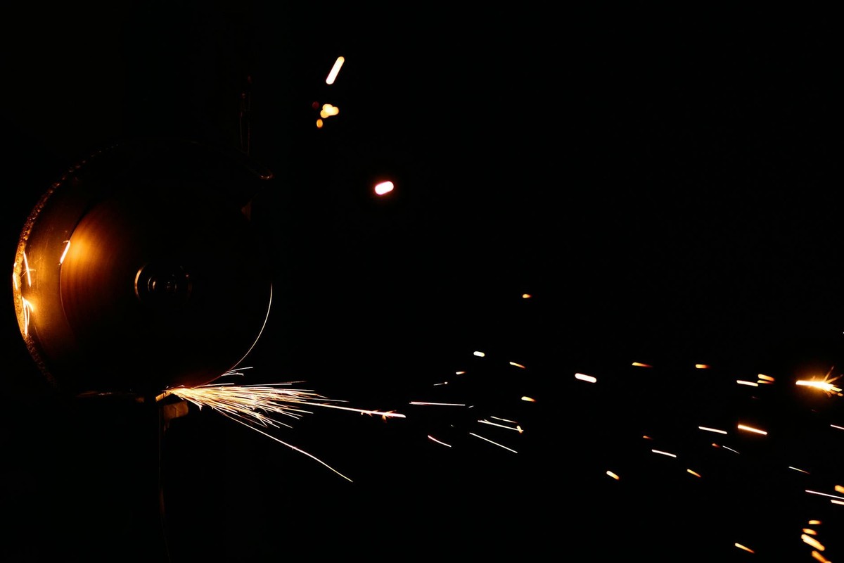 Sparks flying from an angle grinder against a dark background, showcasing vivid motion.