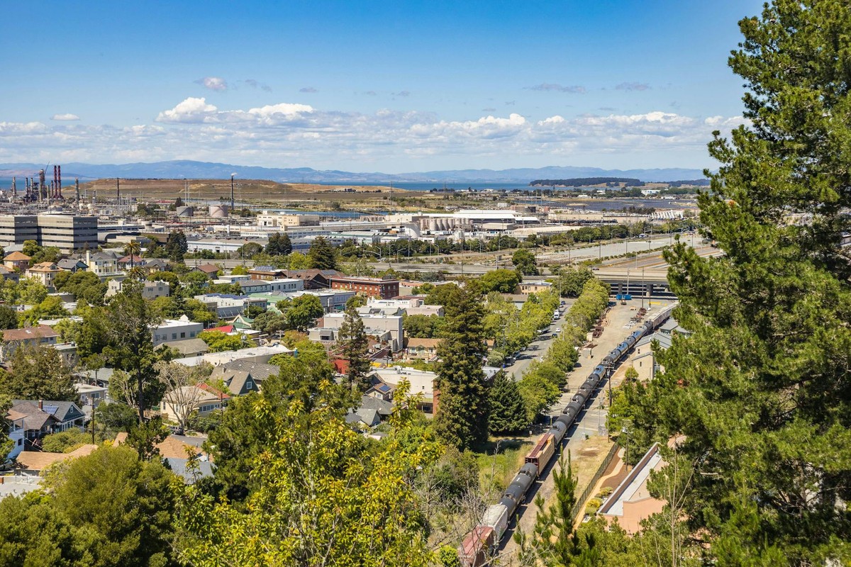 A scenic view of a town with industrial buildings in the distance under a clear blue sky.