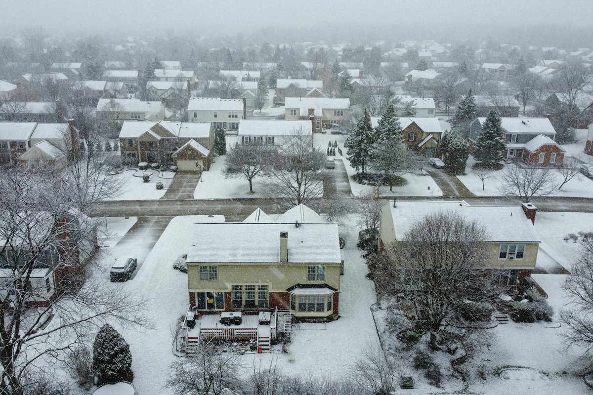 Snow-covered suburban neighborhood with houses and trees in a scenic winter landscape.