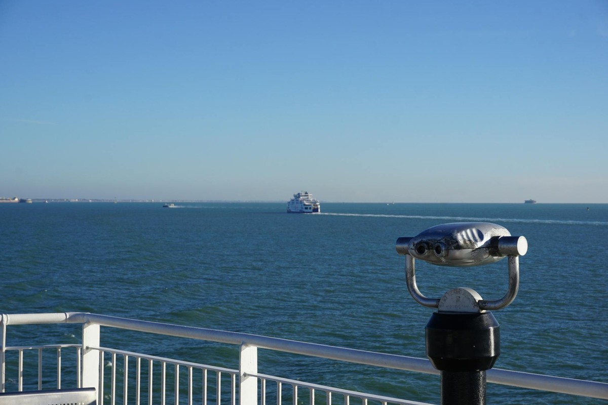 Telescope overlooks the sea with a ferry in the distance at Portsmouth, England.