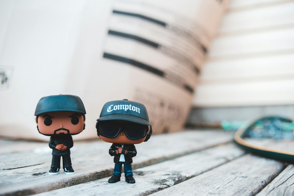 Trendy rappers toys in stylish outfits and caps placed on wooden table on sunny day