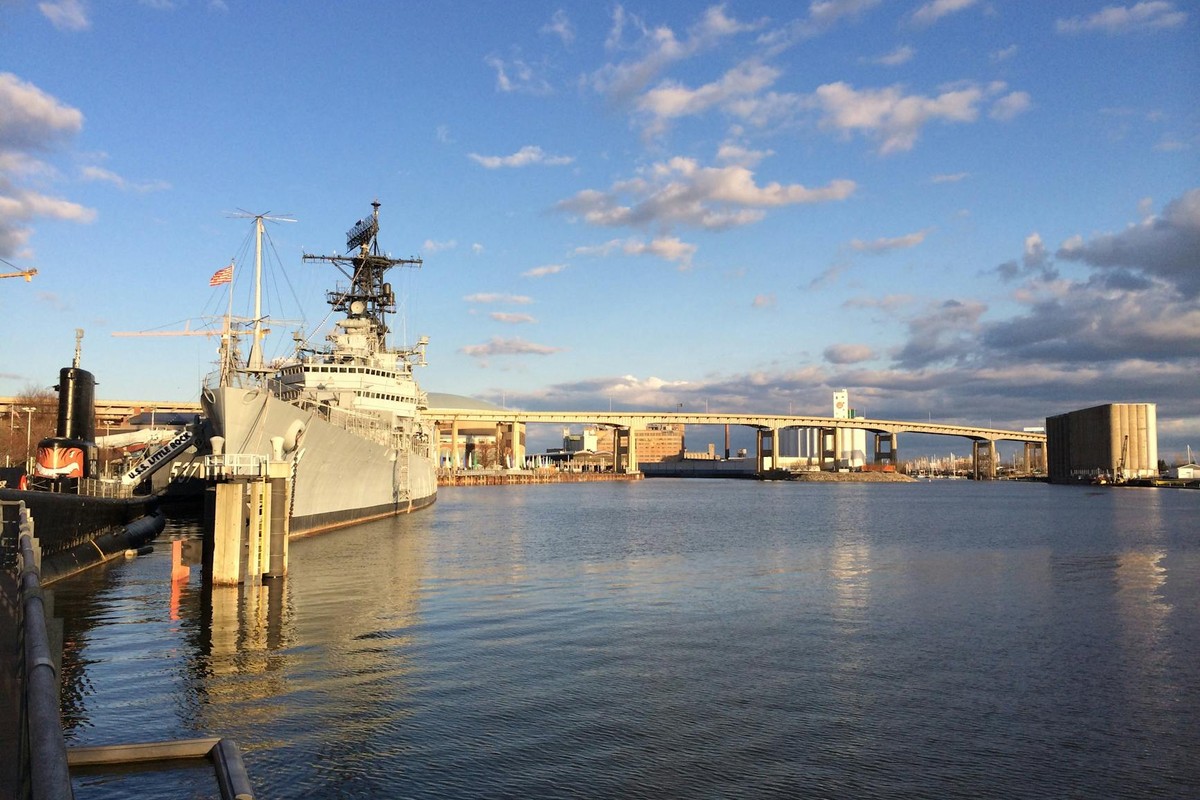 USS Little Rock docked at Buffalo waterfront, with city bridge skyline and serene waters.