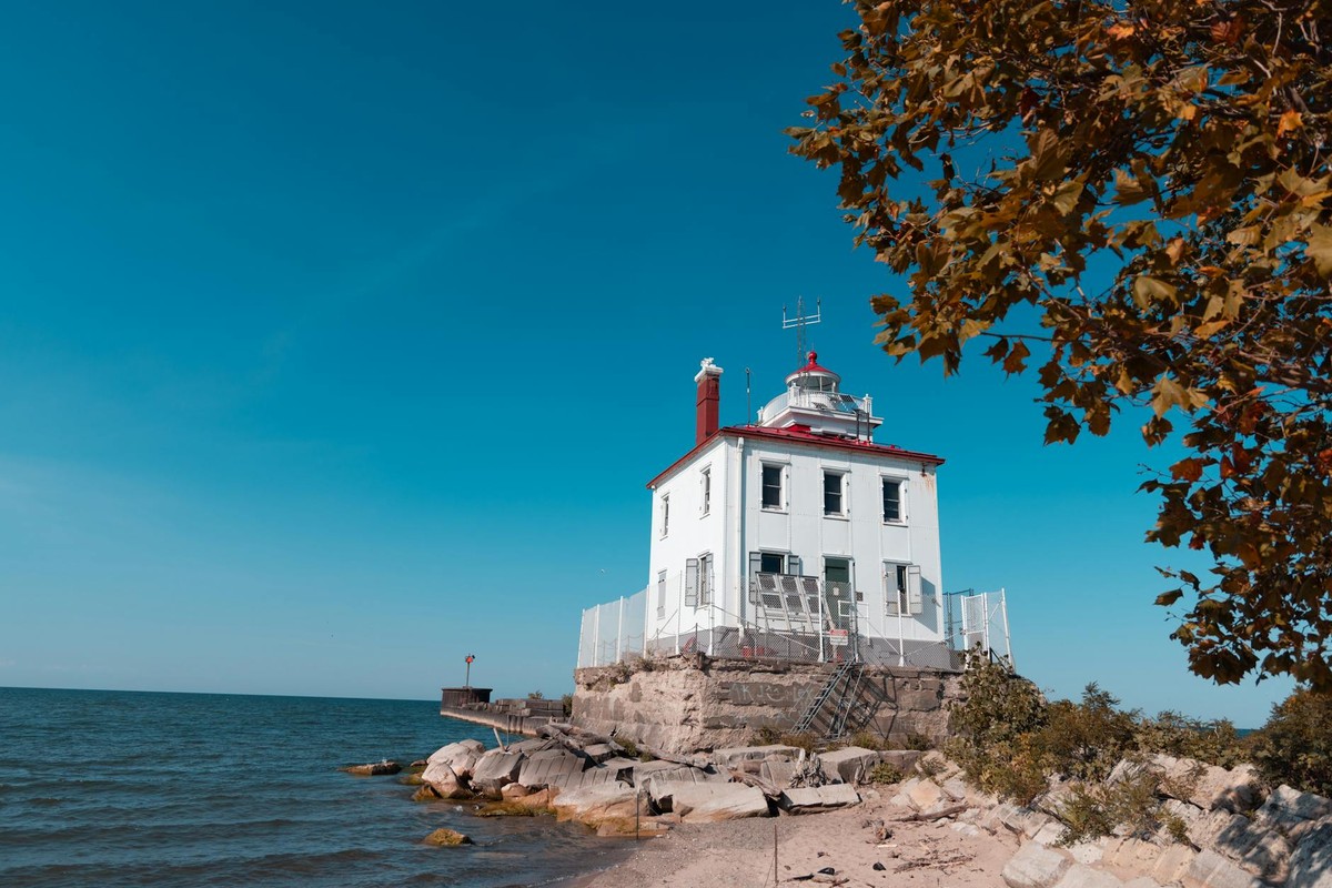 A historic lighthouse on Lake Erie's coast captures the essence of autumn under a clear blue sky.