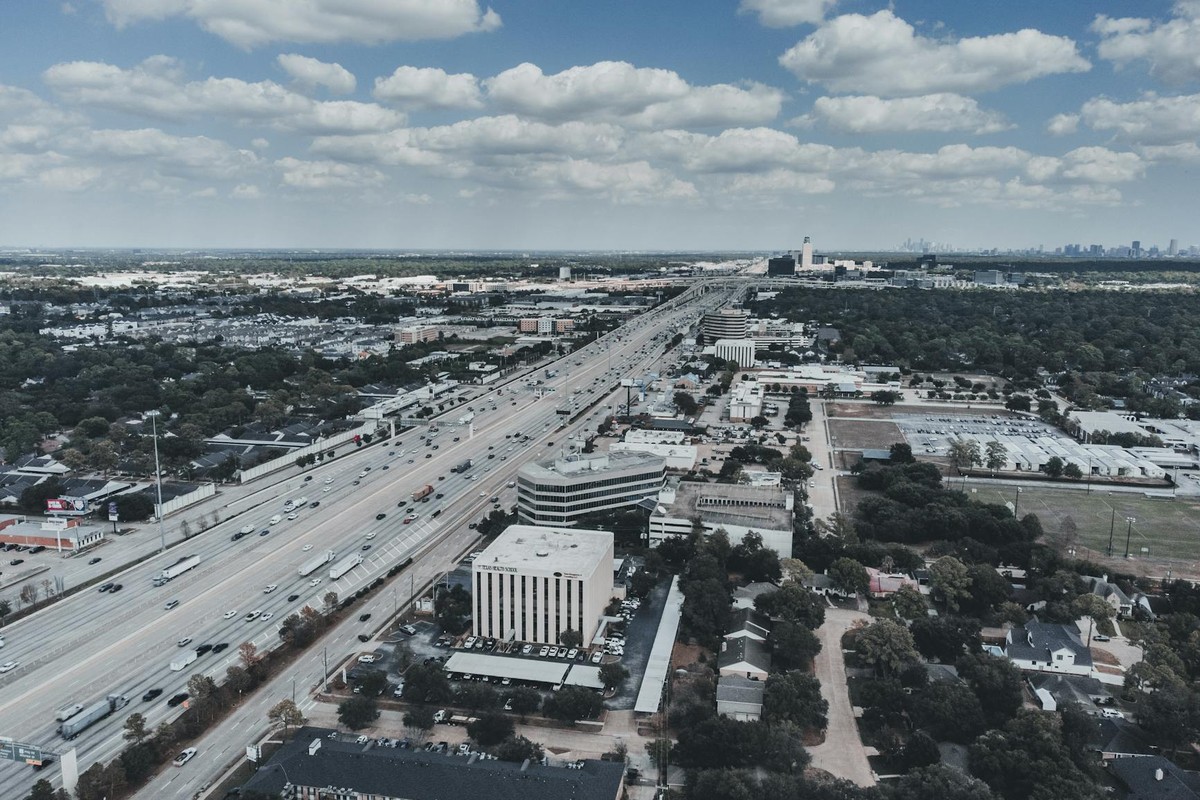 Expansive aerial cityscape with highway, showcasing urban development and open sky.
