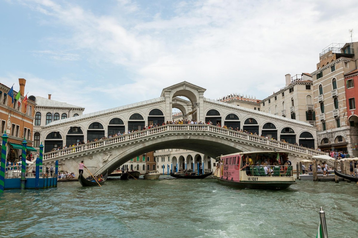 Iconic Rialto Bridge spanning the Grand Canal in Venice, Italy on a sunny day.