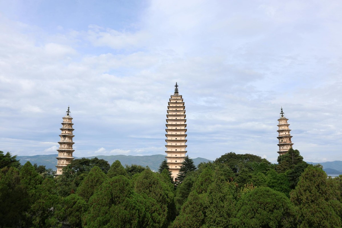 Elegant view of the Three Pagodas in Dali, China, framed by lush greenery and distant mountains.