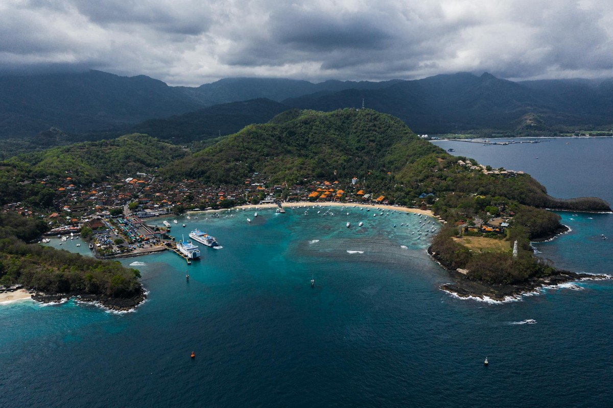Stunning aerial view of Padang Bai Beach in Bali with clear turquoise waters and lush greenery.