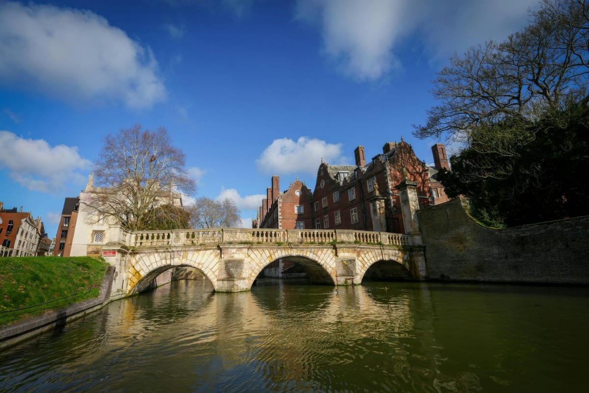 Capture of a historic stone bridge in Cambridge with clear blue skies and classic architecture.