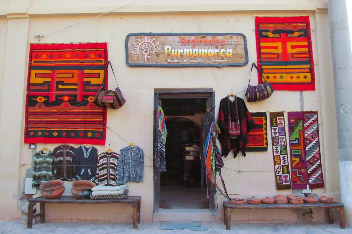 Colorful textile shop facade in Purmamarca, Argentina showcasing traditional Andean clothing and crafts.