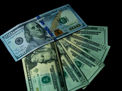 Close-up image of varied US dollar bills on a black background.