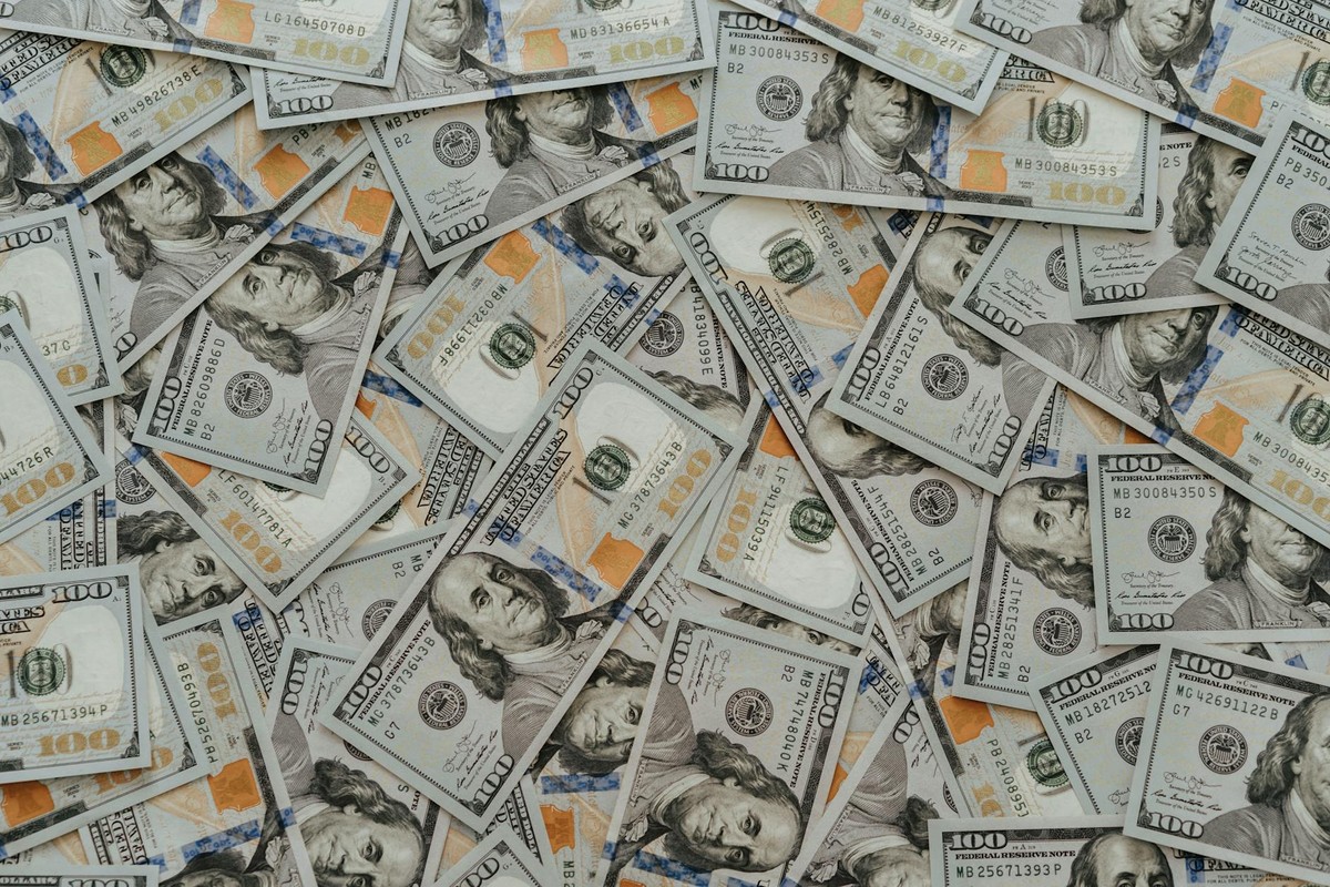 US hundred dollar bills scattered in abundance creating a financial backdrop.