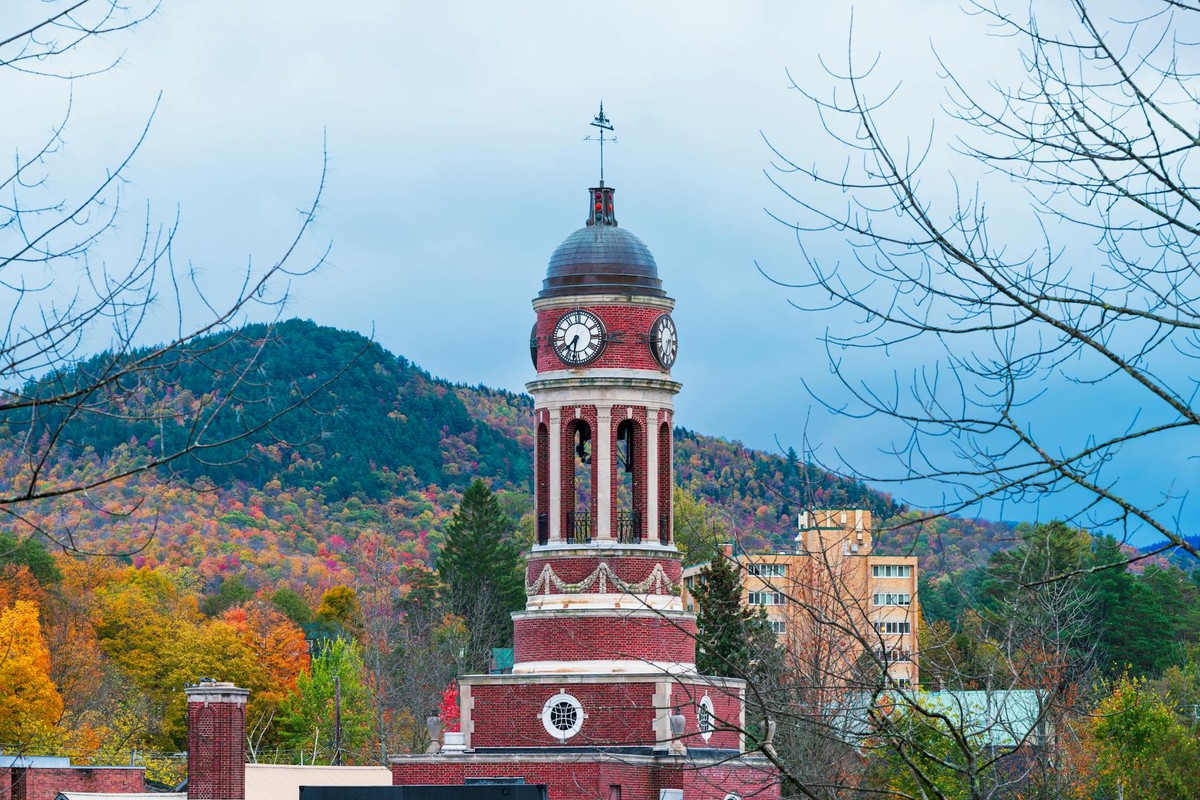 Historic clock tower amidst vibrant autumn foliage in the Adirondack Mountains.