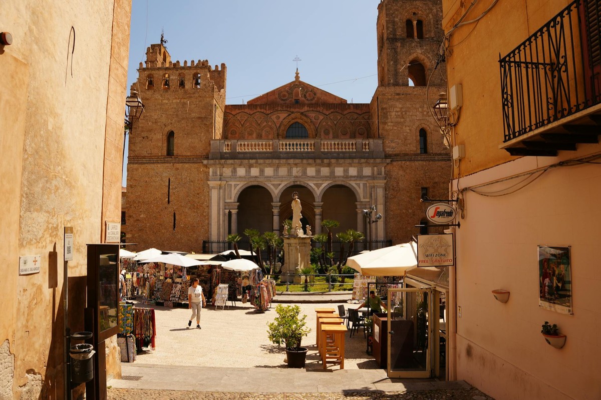 Explore the stunning Norman architecture of Monreale Cathedral in Sicily's lively street setting.