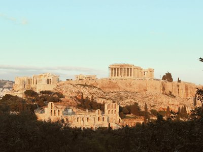 The iconic Acropolis of Athens, a UNESCO World Heritage Site, bathed in warm sunset light.