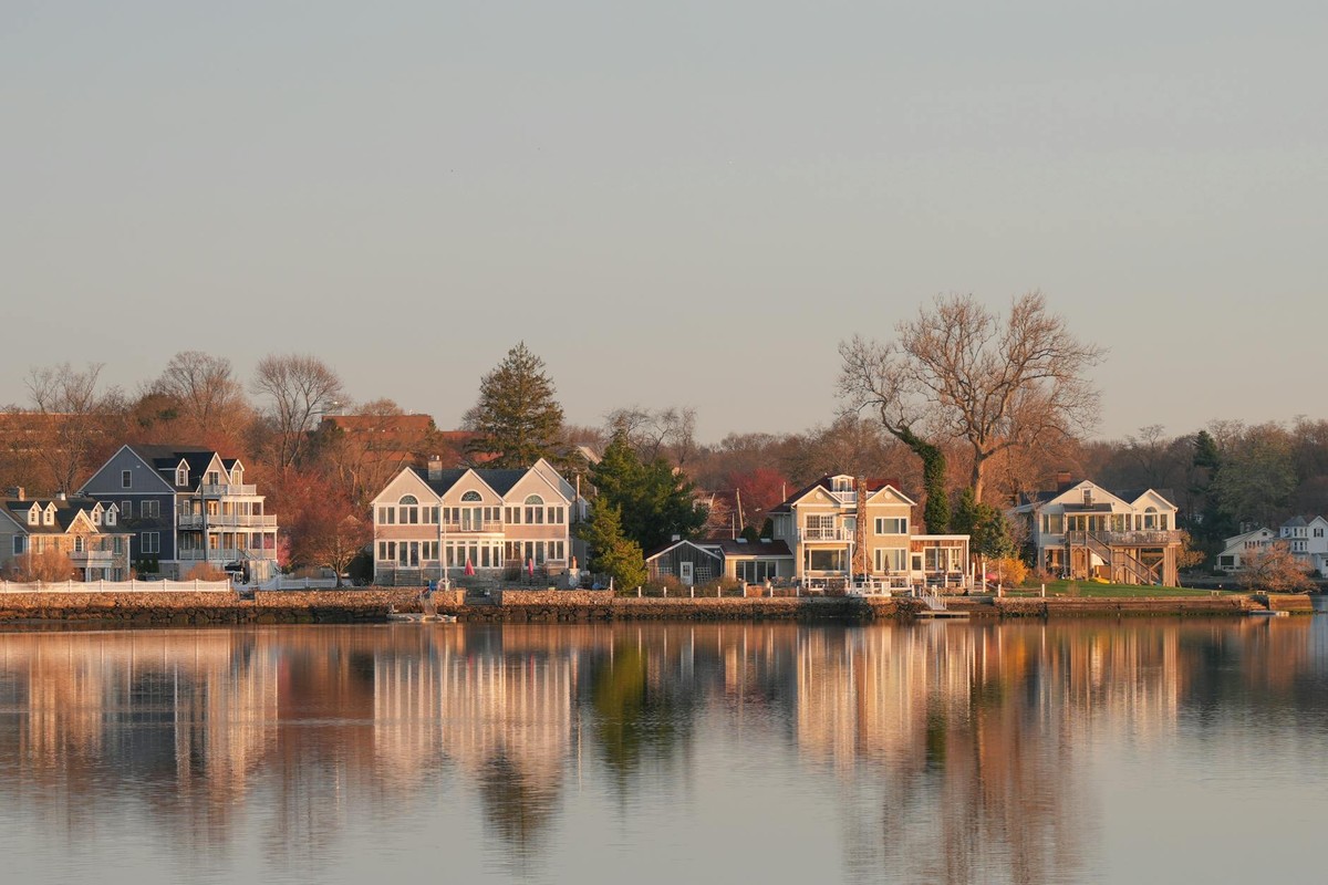 Scenic view of waterfront homes in Stamford, Connecticut at sunrise, with reflections on calm waters.