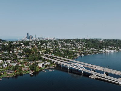 Scenic aerial shot of Seattle skyline with bridge spanning across a lake on a clear day.