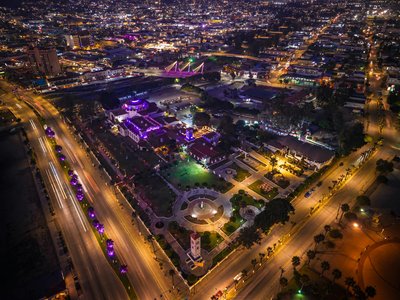 Vibrant aerial night view of Ensenada cityscape with illuminated streets and buildings.