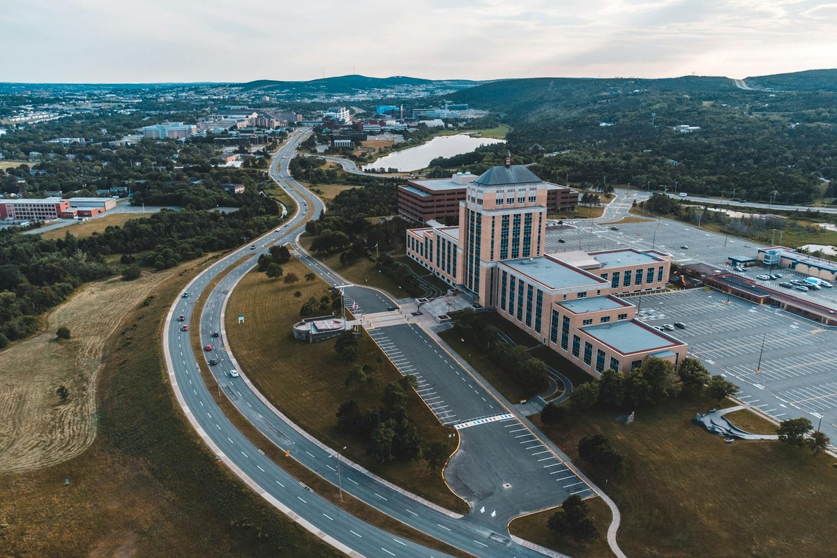 A scenic aerial view of the Confederation Building with roadways and greenery in Newfoundland and Labrador.