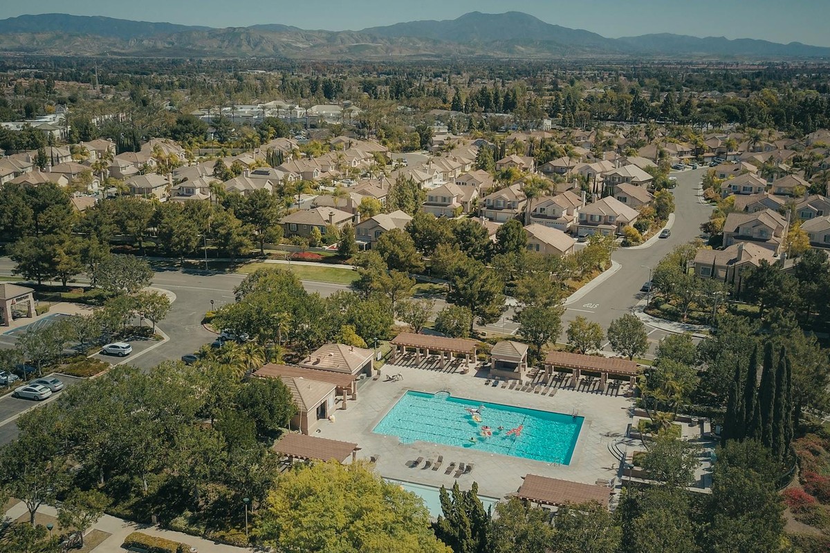 Aerial shot of a suburban neighborhood featuring a community swimming pool on a sunny day.