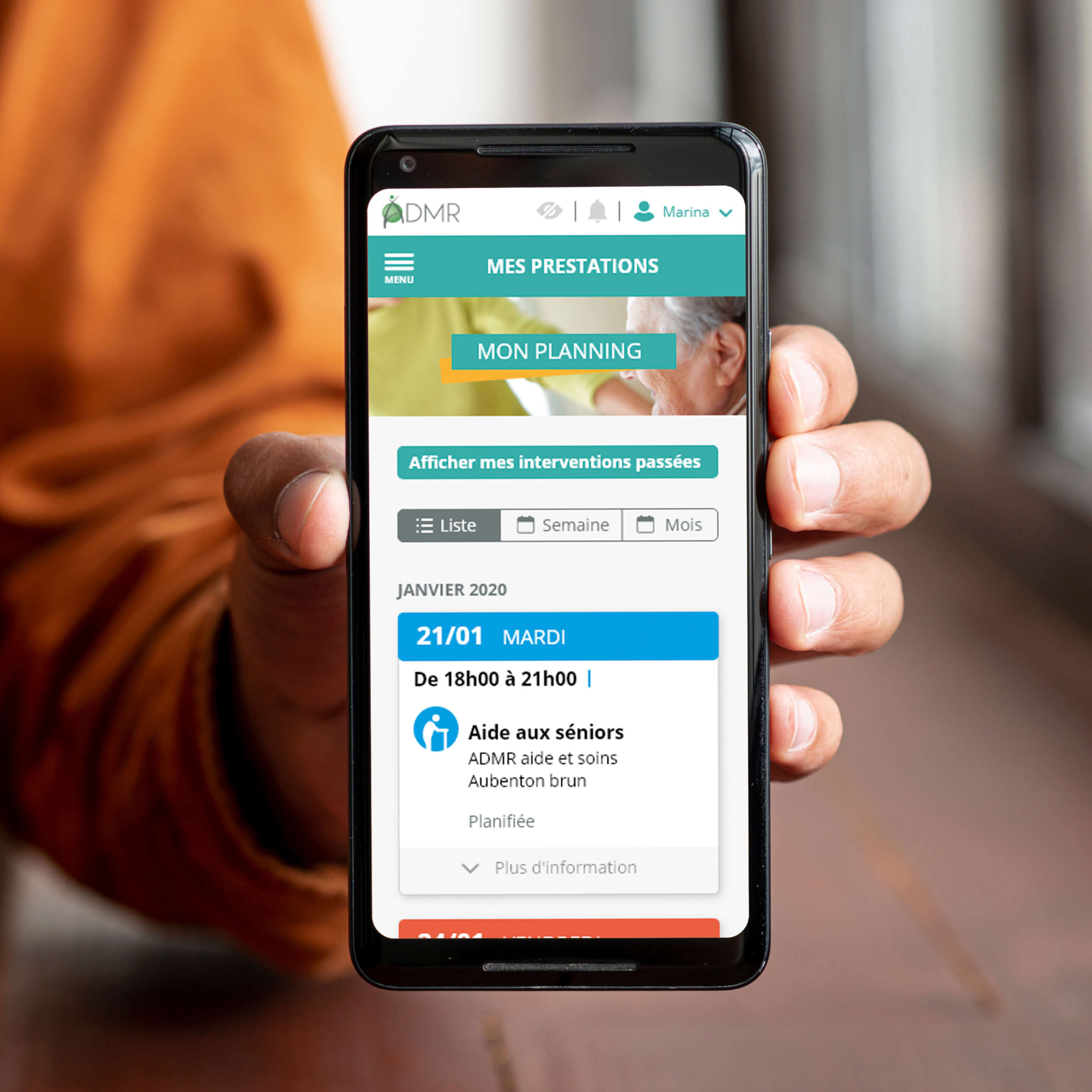 Hand holding a phone showing the home screen of ADMR customer area.