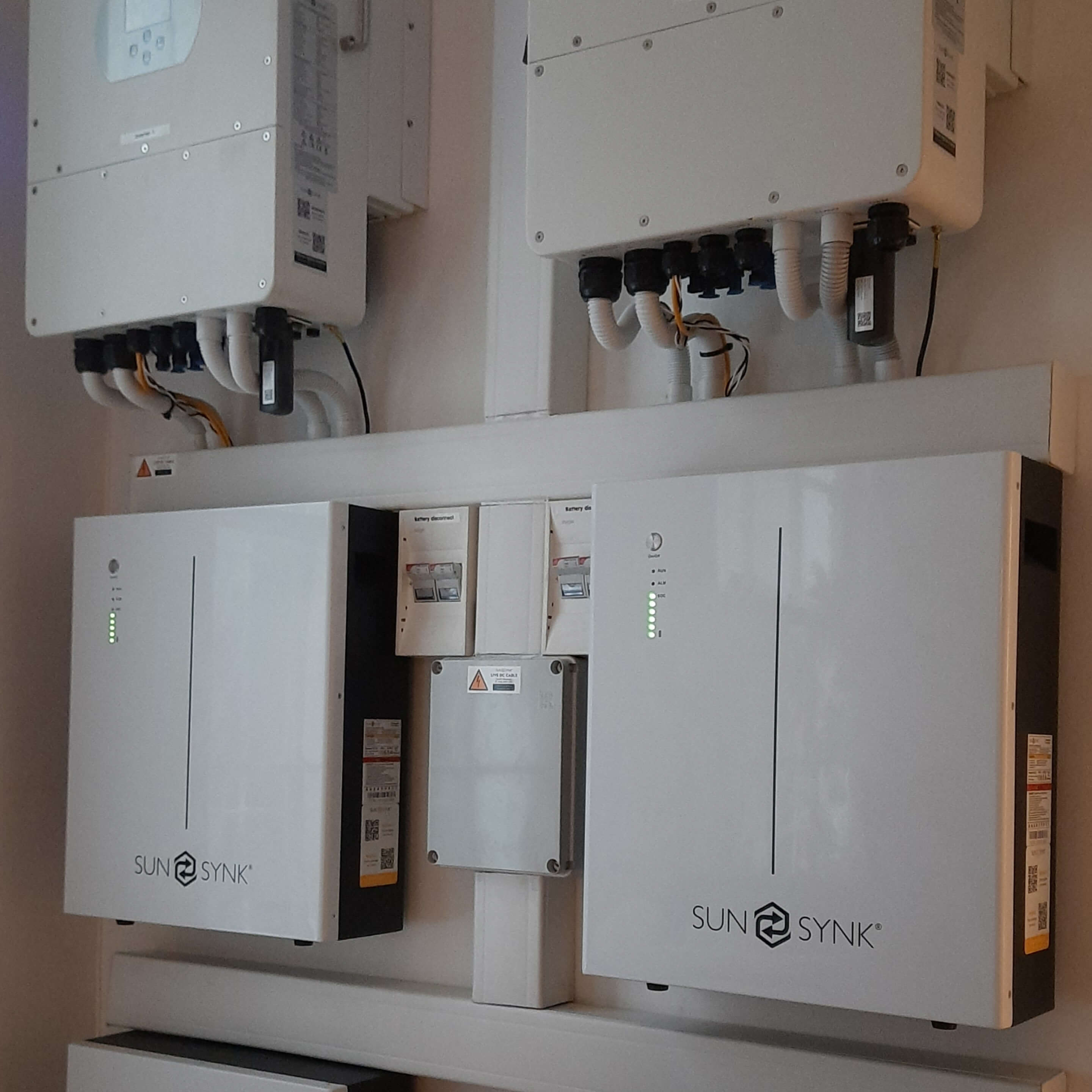 Existing solar installation, several inverters and batteries next to each other.