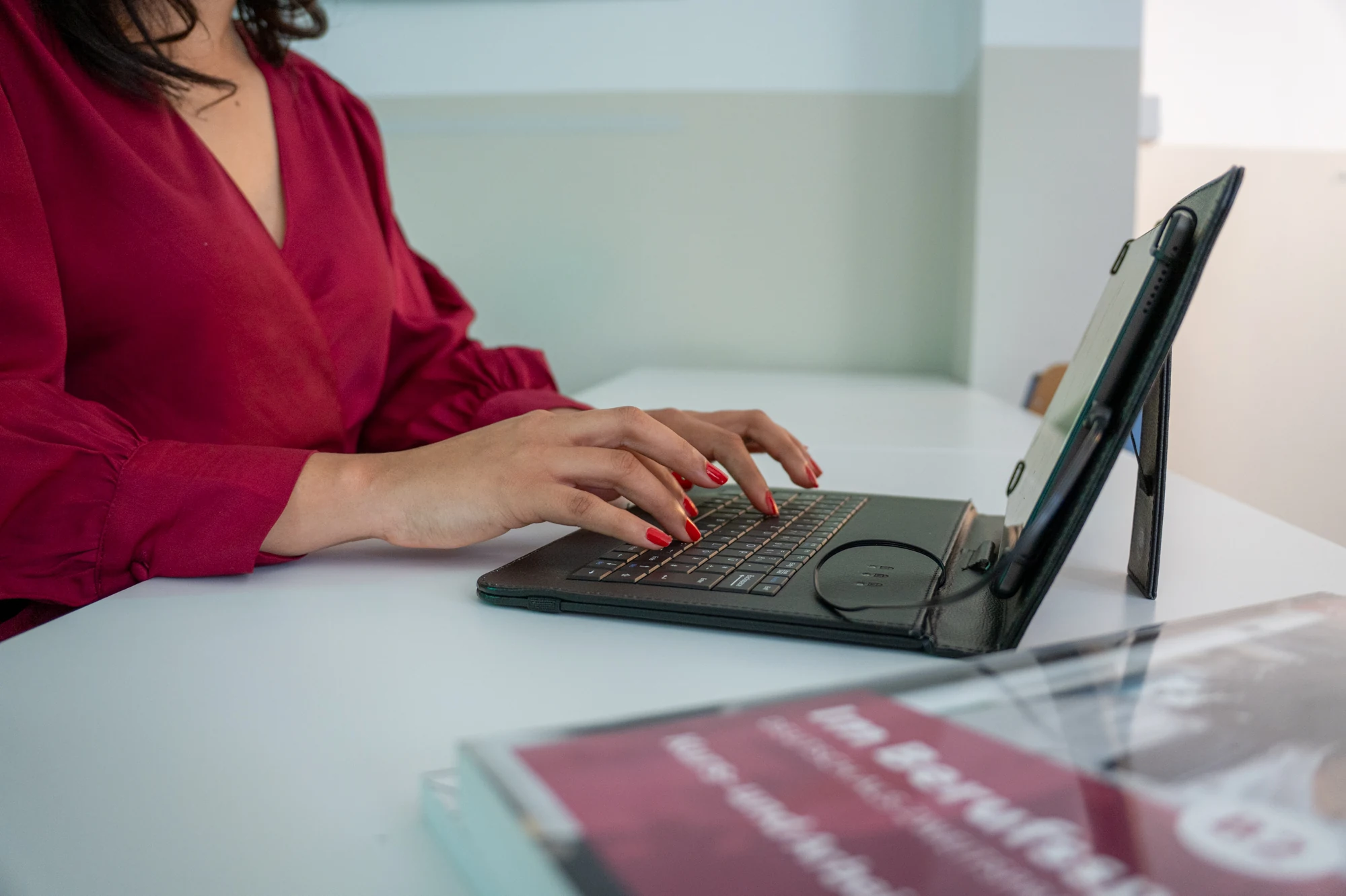 Frau mit rotem Hemd tippt auf einer Tastatur, die mit einem Tablet verbunden ist.