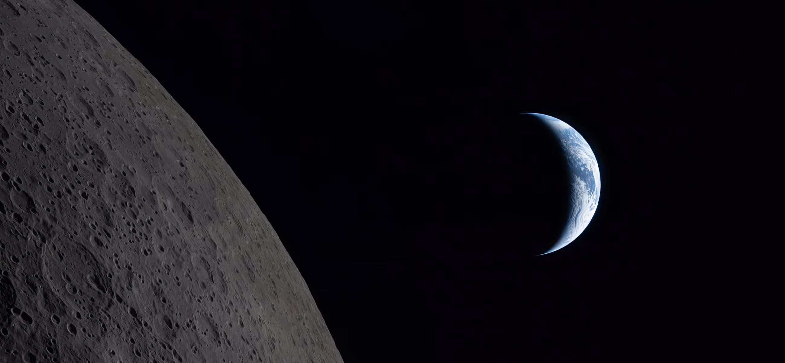 View of Earth's crescent shining in space with the moon's cratered surface in the foreground.