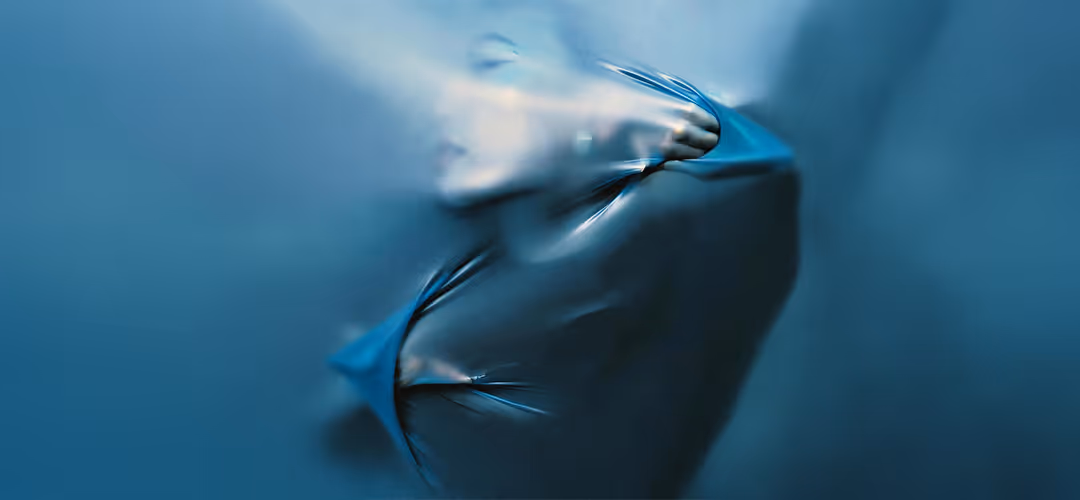 Blurred human face pressing against a smooth translucent blue surface.