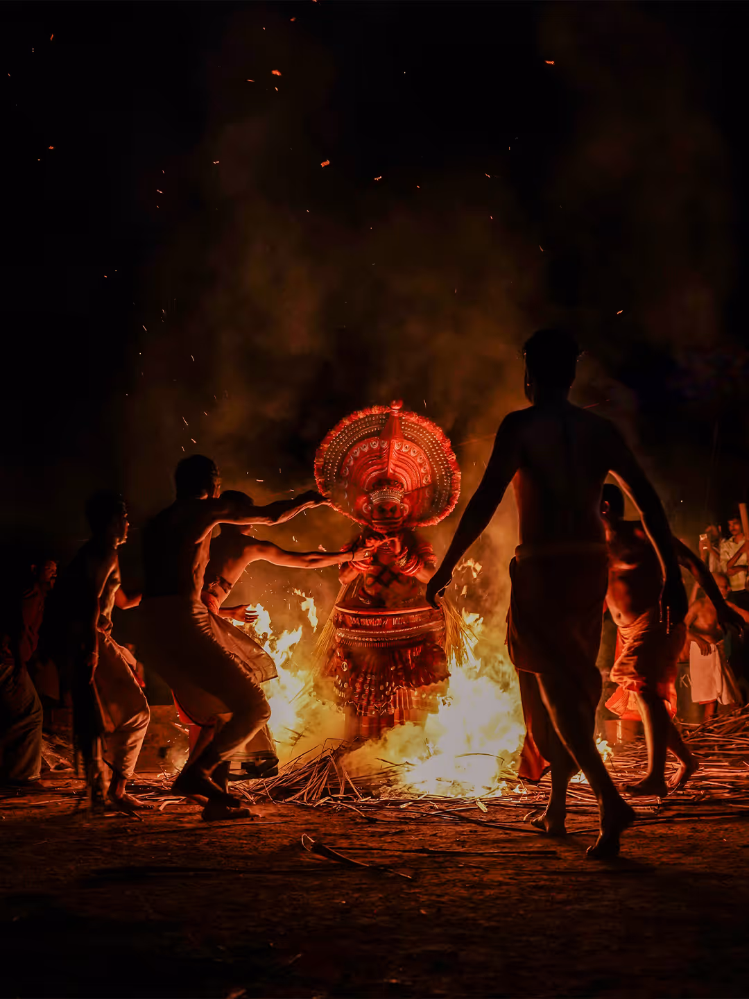 People surrounding a performer in traditional costume dancing around fire at night.