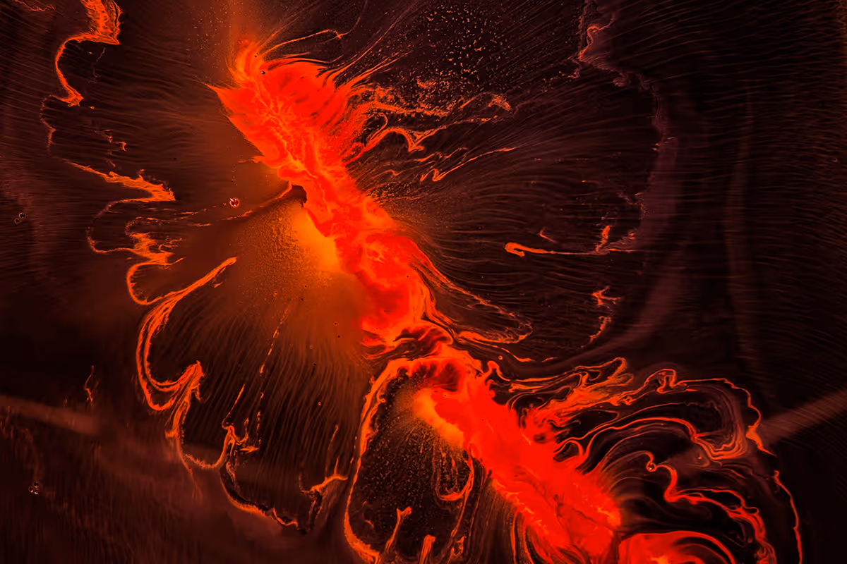 Close-up of bright red-orange molten lava flowing and glowing on a dark surface.