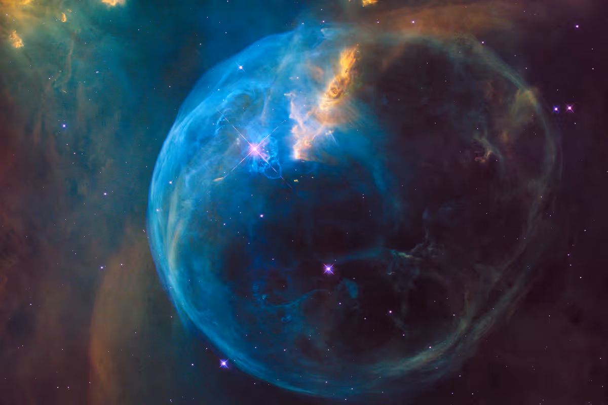 Blue and orange glowing nebula shaped like a large bubble in deep space with scattered stars.