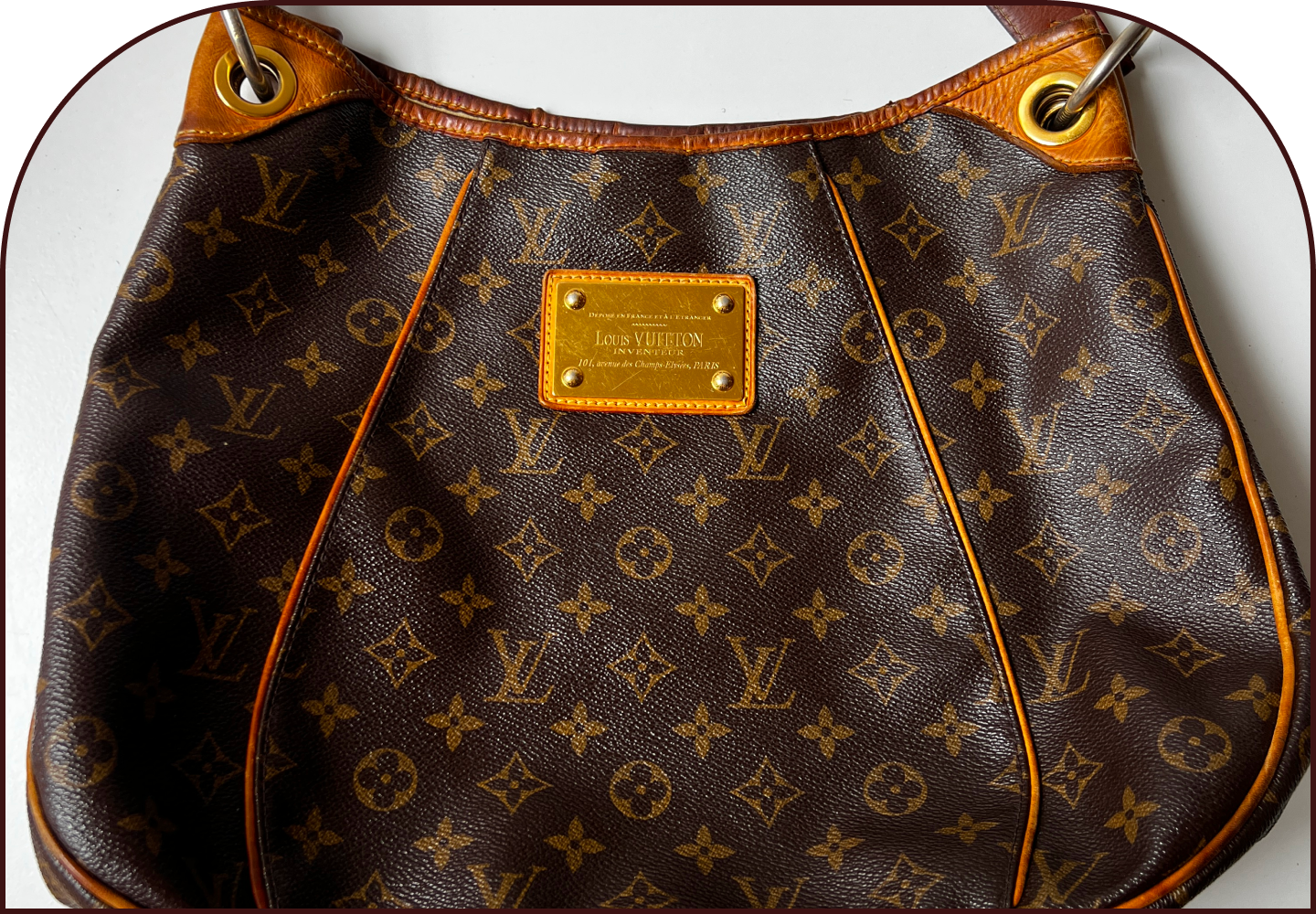 Close-up of a Louis Vuitton Galliera monogram canvas hobo bag with brass logo plaque and tan leather trim, prior to restoration.