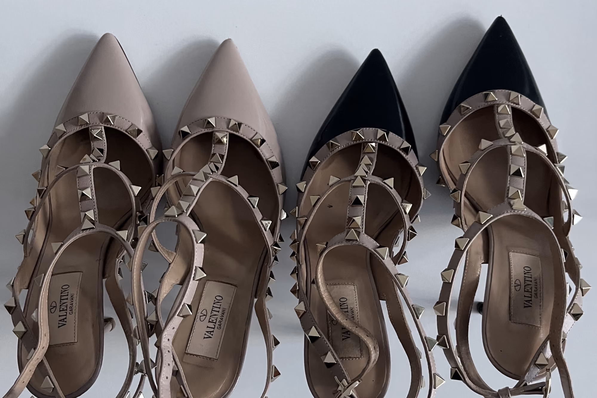 Two pairs of Valentino Rockstud caged heels, nude and black, side by side after restoration by The Reco Lab.