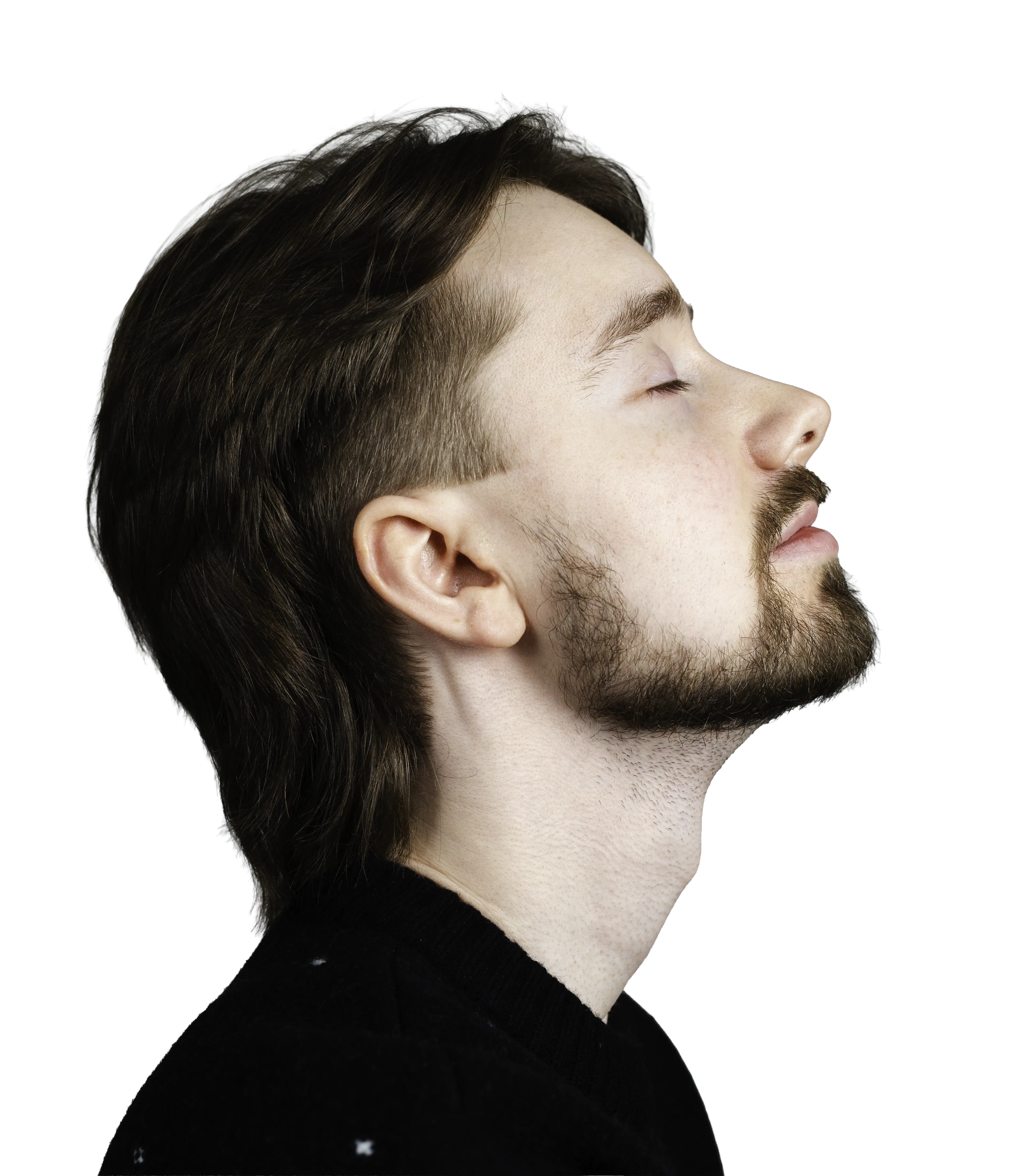 Side profile of a man with closed eyes and a beard, wearing a black sweater.