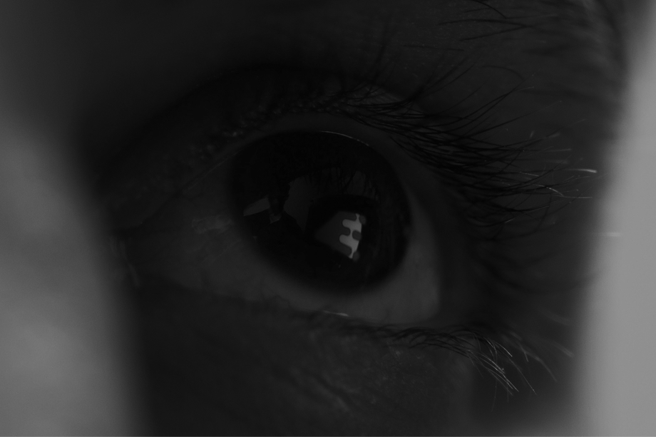 Gros plan en noir et blanc d'un œil humain avec des cils longs et une réflexion lumineuse dans la pupille.