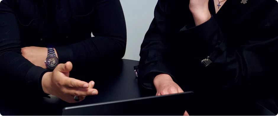 Deux personnes discutant devant un ordinateur portable ouvert sur une table ronde.