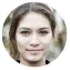 Portrait of a young woman with light makeup, brown hair tied back, and a neutral expression.